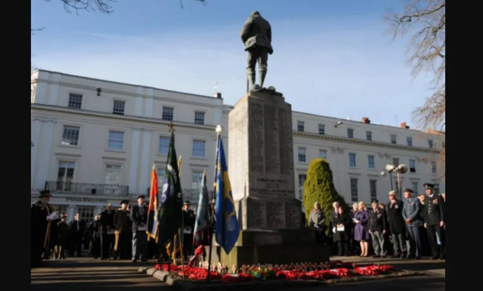 Crowd and standard bearers around a war memorial at a Remembrance service
