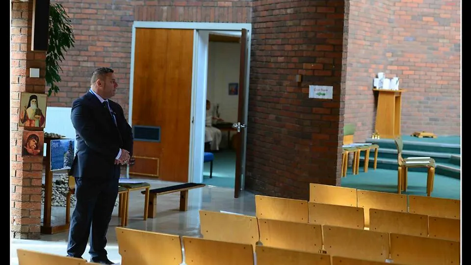 Security officer standing inside a hall with rows of chairs